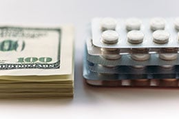 A stack of money next to prescription medication