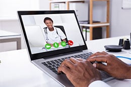 A person speaking to a doctor on a computer screen